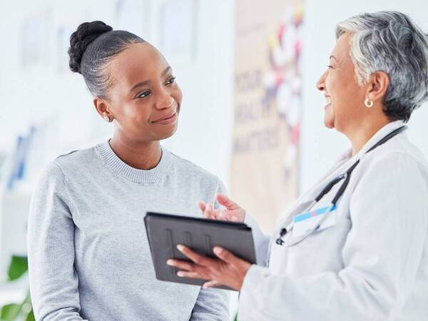 A young black woman smiles as she consults with her doctor.